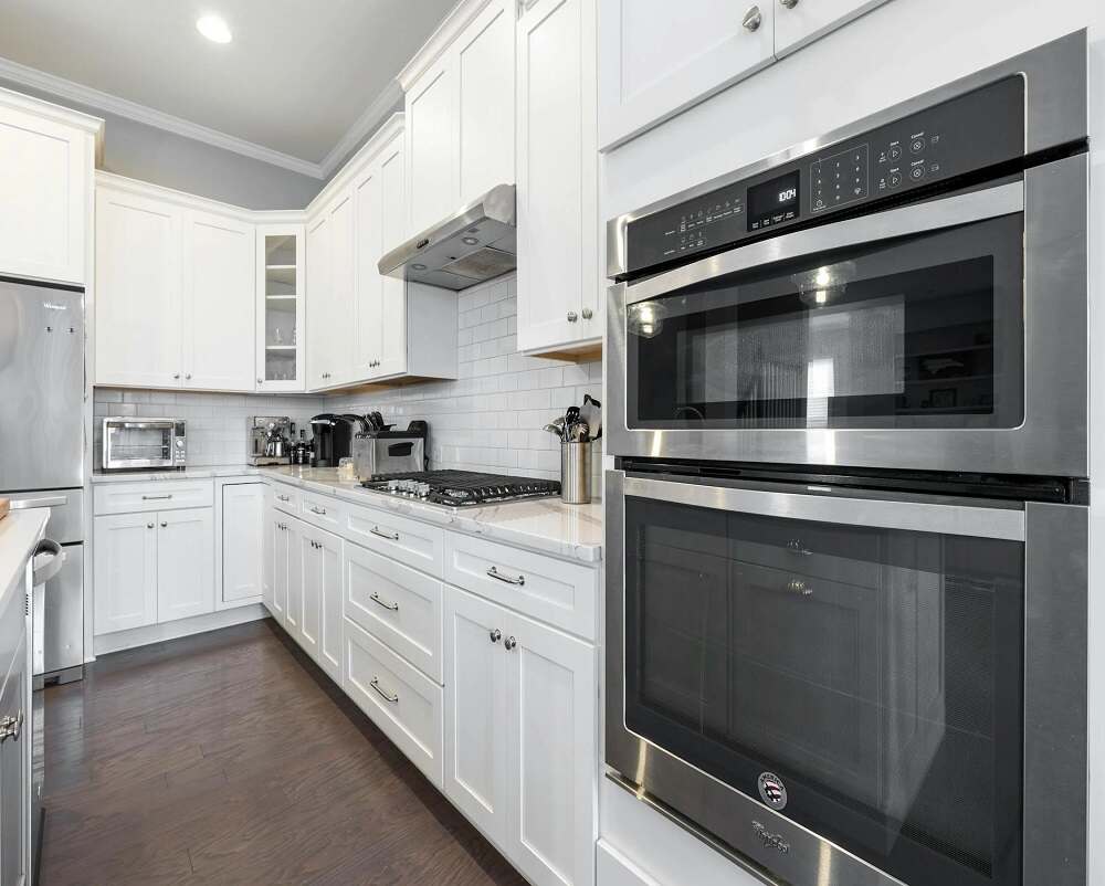 a kitchen with white cabinets and stainless steel oven