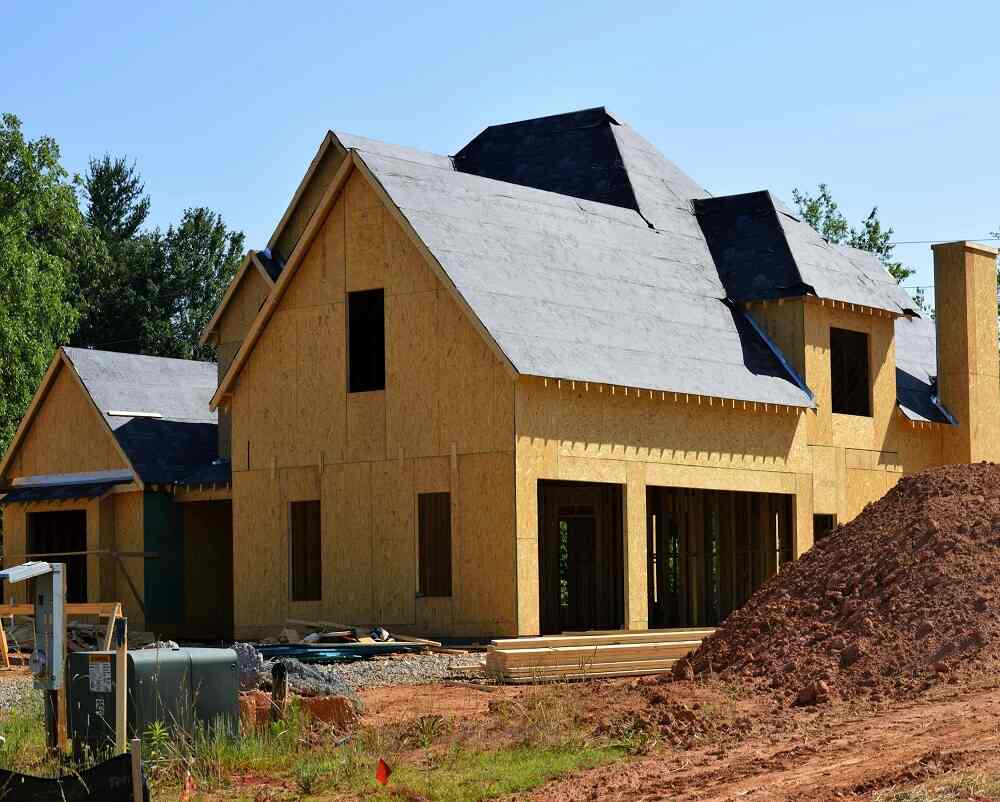 a house under construction with dirt and trees