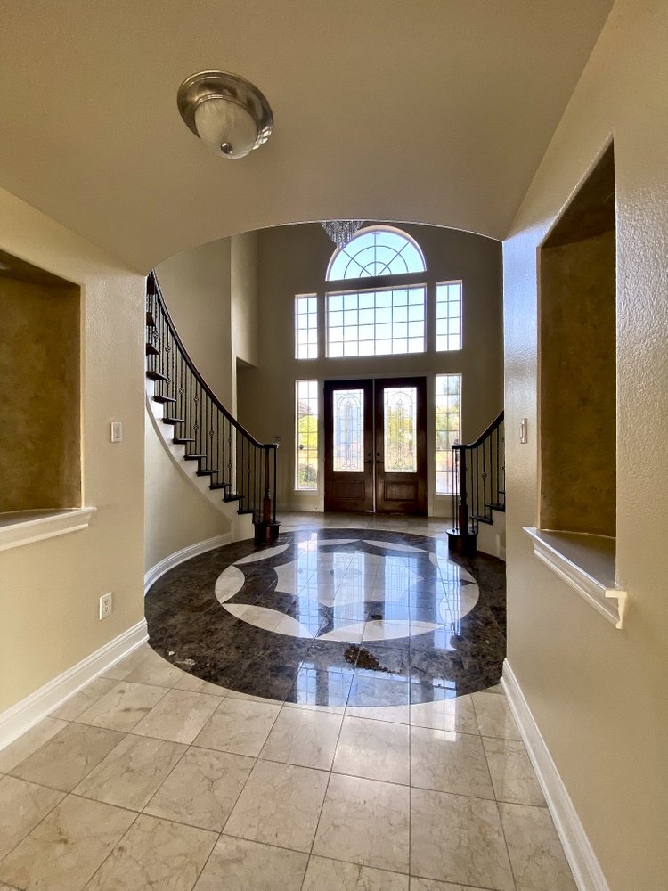 "Elegant home foyer with marble flooring and curved staircase, ideal for home renovation and construction projects."