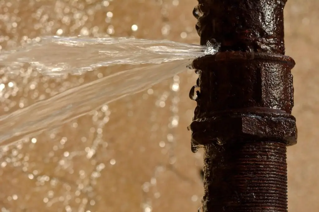 Damaged water pipe caused by freezing temperatures, showing cracks and water leakage.